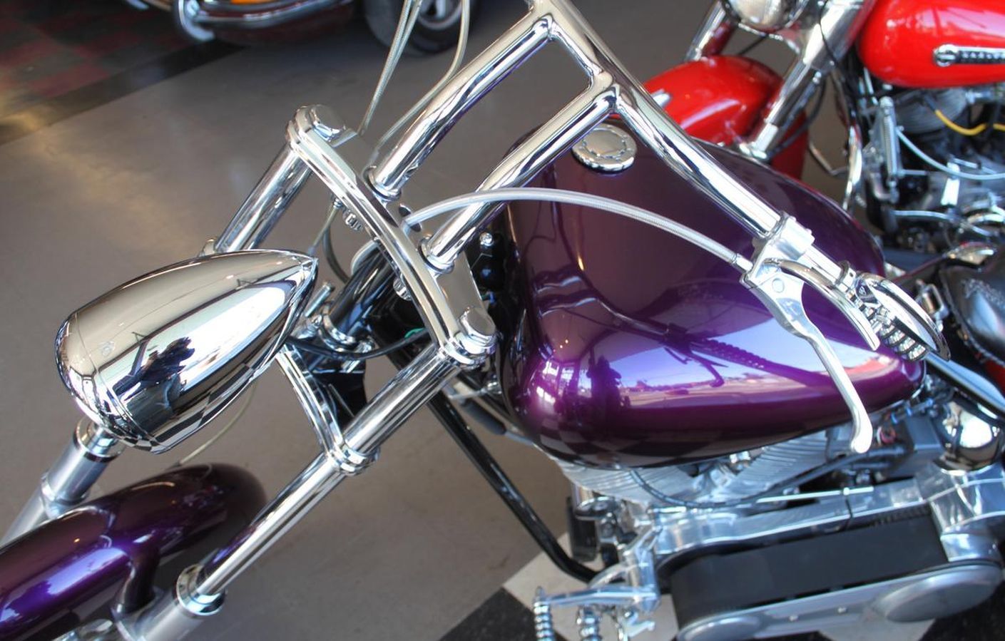 A purple motorcycle is parked next to a red motorcycle