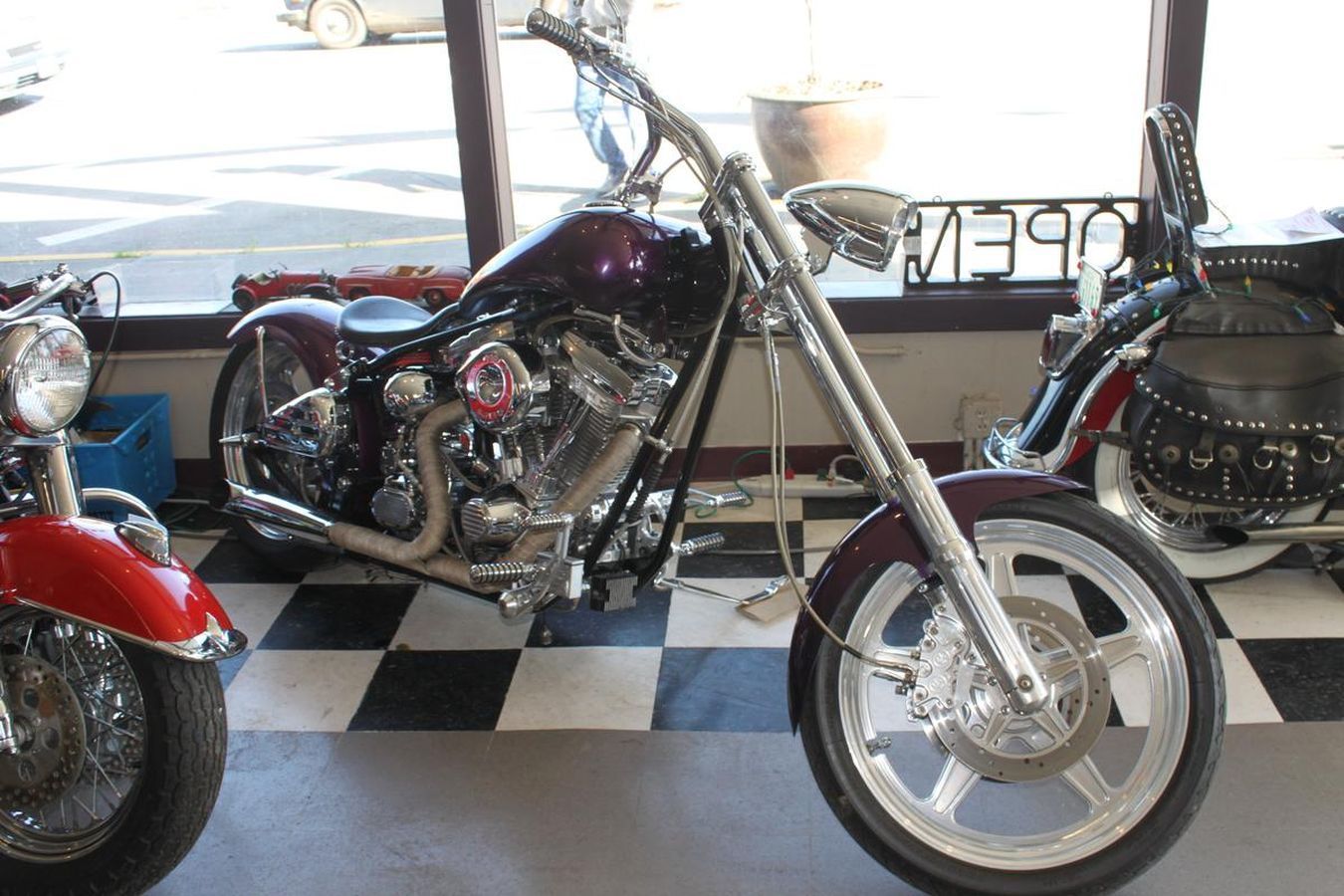 A motorcycle is parked in front of a sign that says open