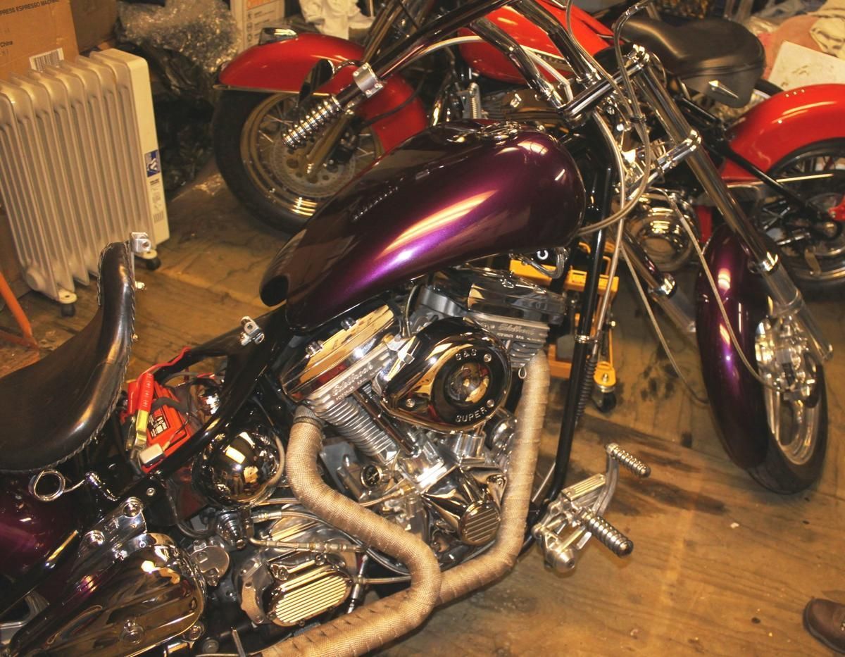 A purple motorcycle is parked next to a red motorcycle