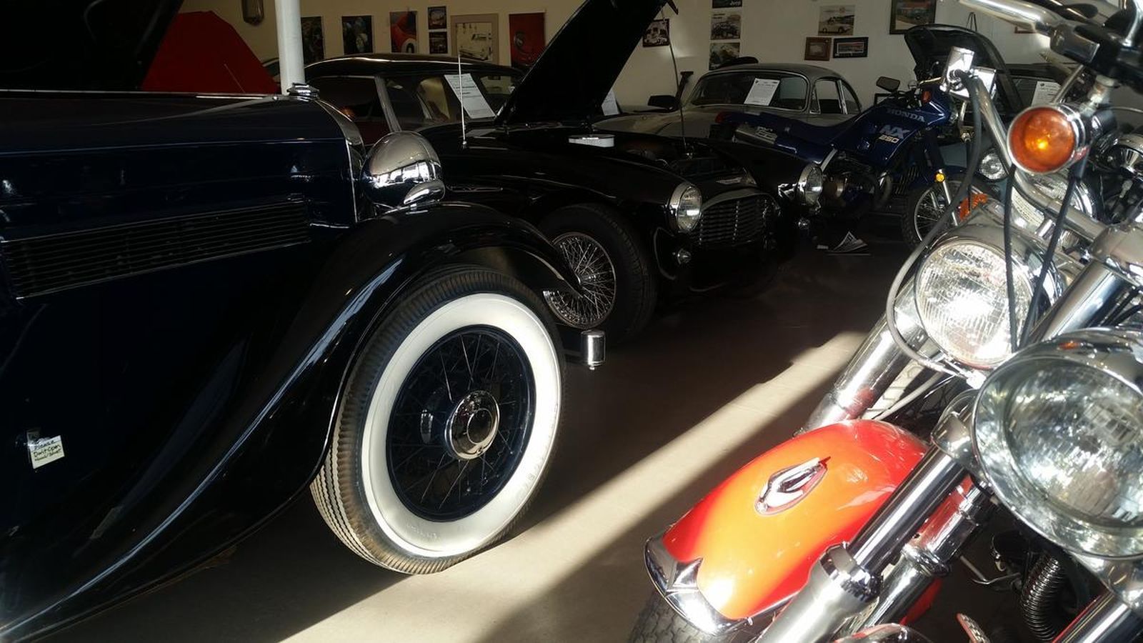 A row of old cars and motorcycles in a garage