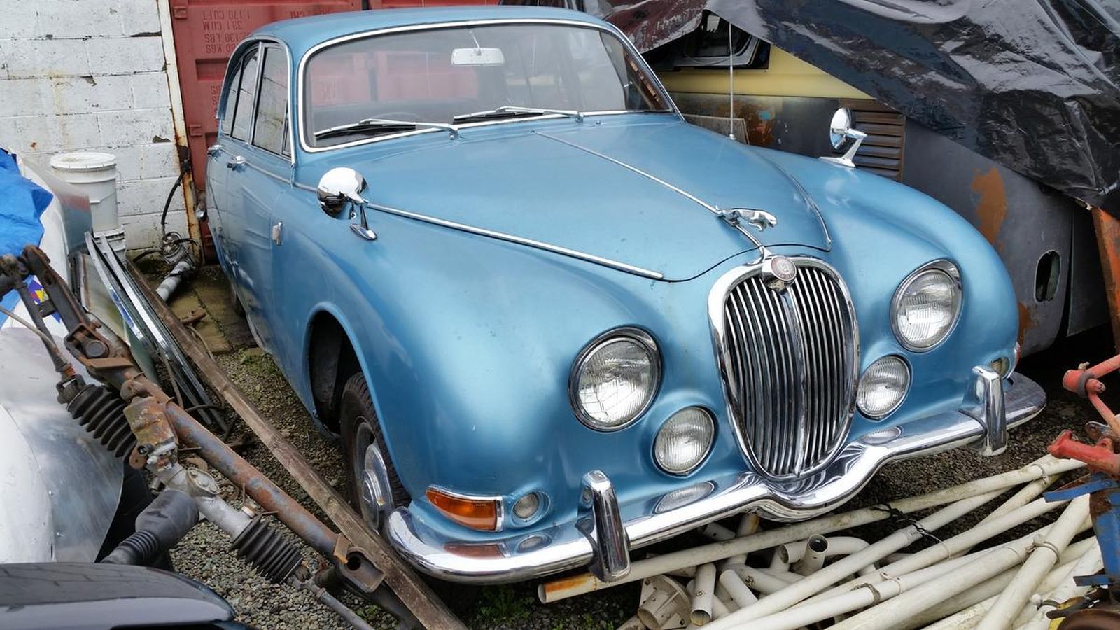 A blue car is sitting on top of a pile of junk.