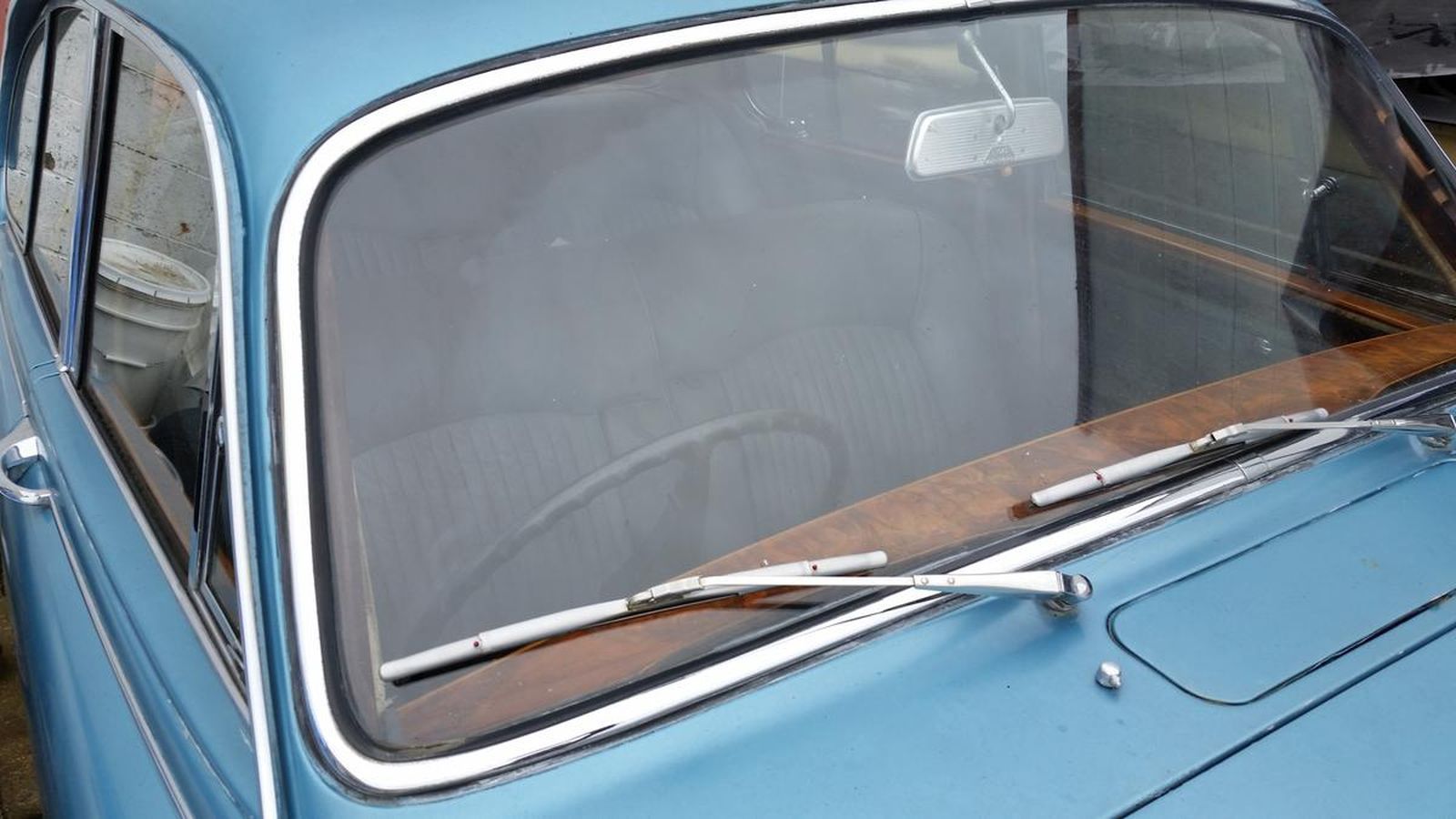 A close up of a blue car with a windshield and wiper.