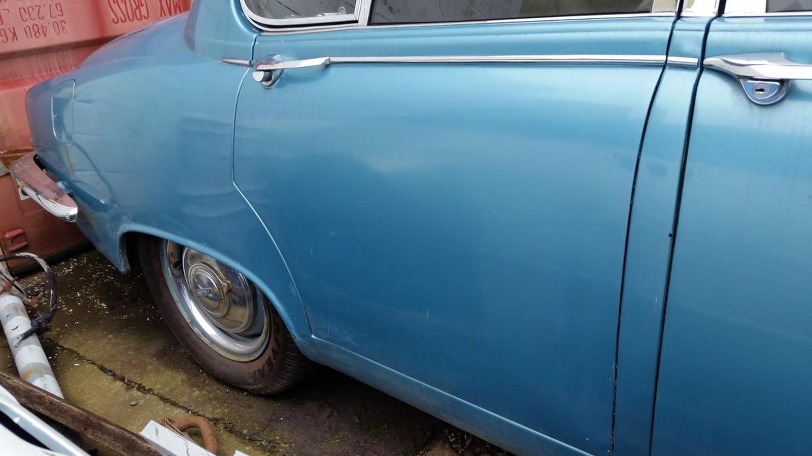 A blue car is parked on the side of the road.