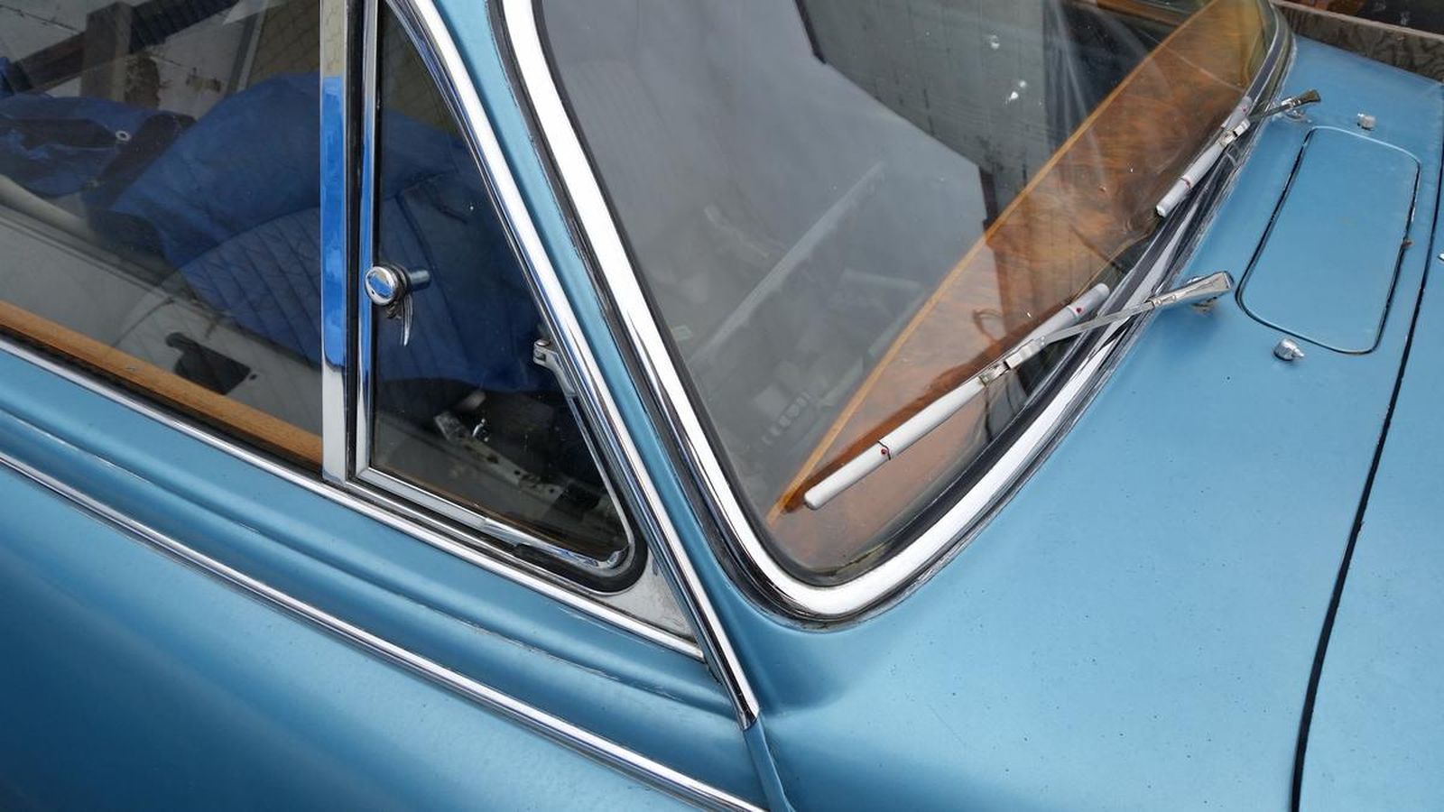 A close up of a blue car with a wooden windshield