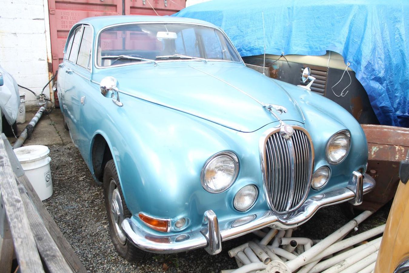 A blue jaguar car is parked in front of a blue tarp