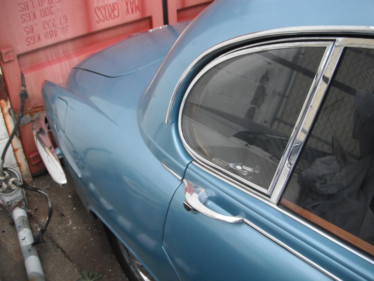 A blue car is parked next to a red shipping container