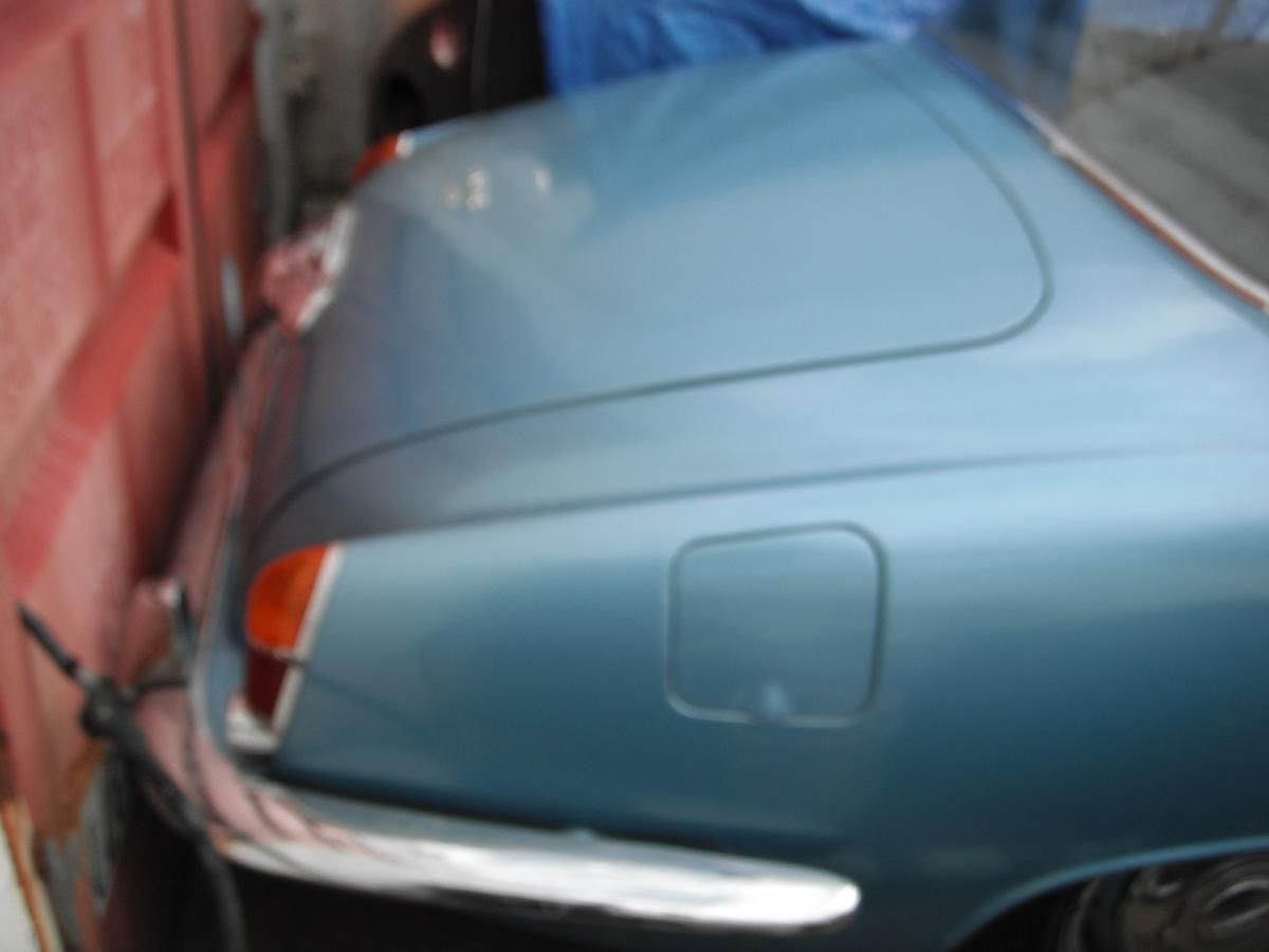 A blue car is parked next to a red wall