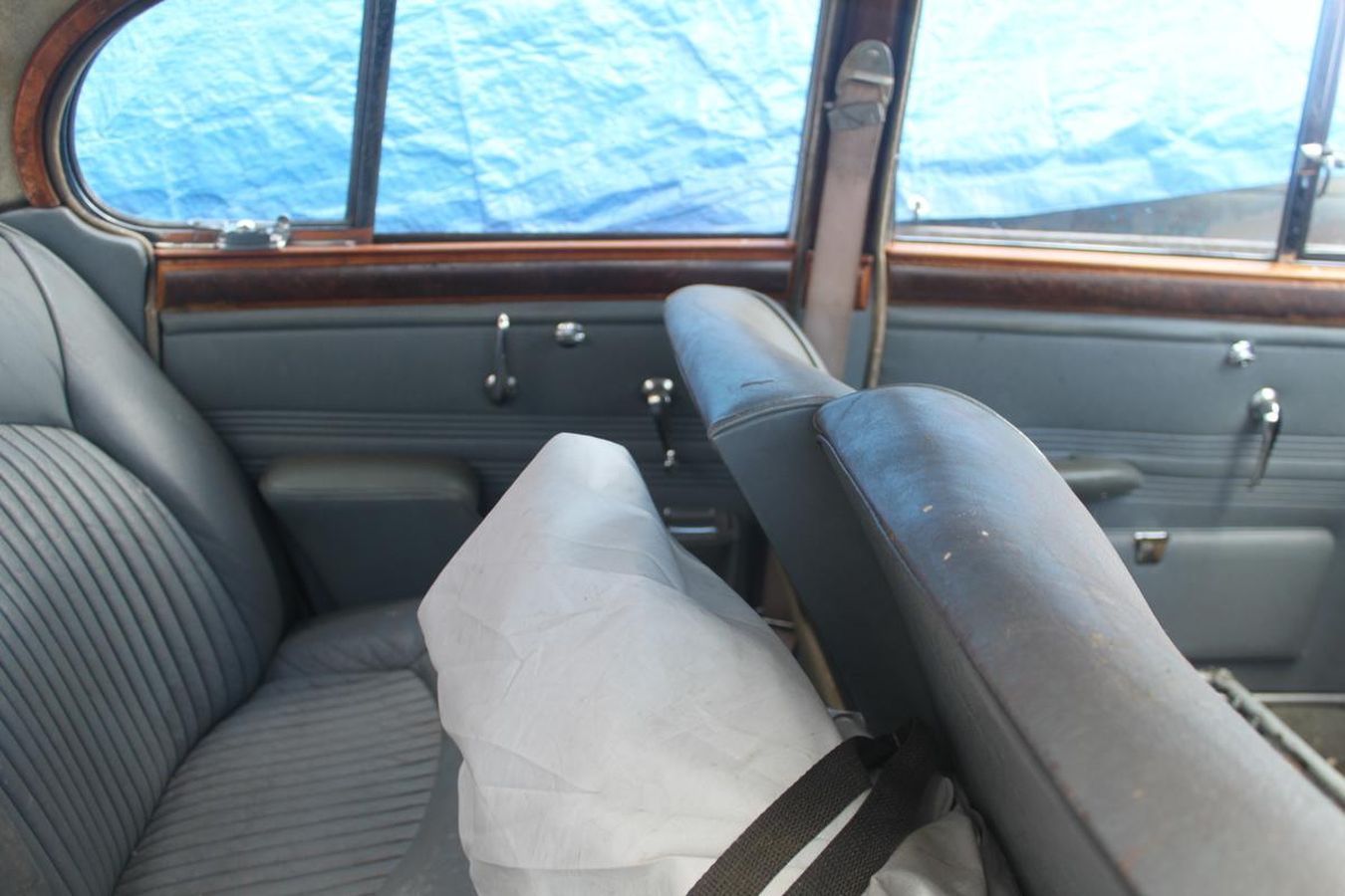 The back seat of a car with a blue tarp covering the window