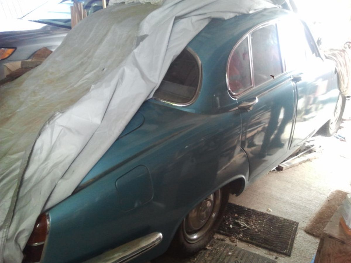 A blue car is covered with a white cloth