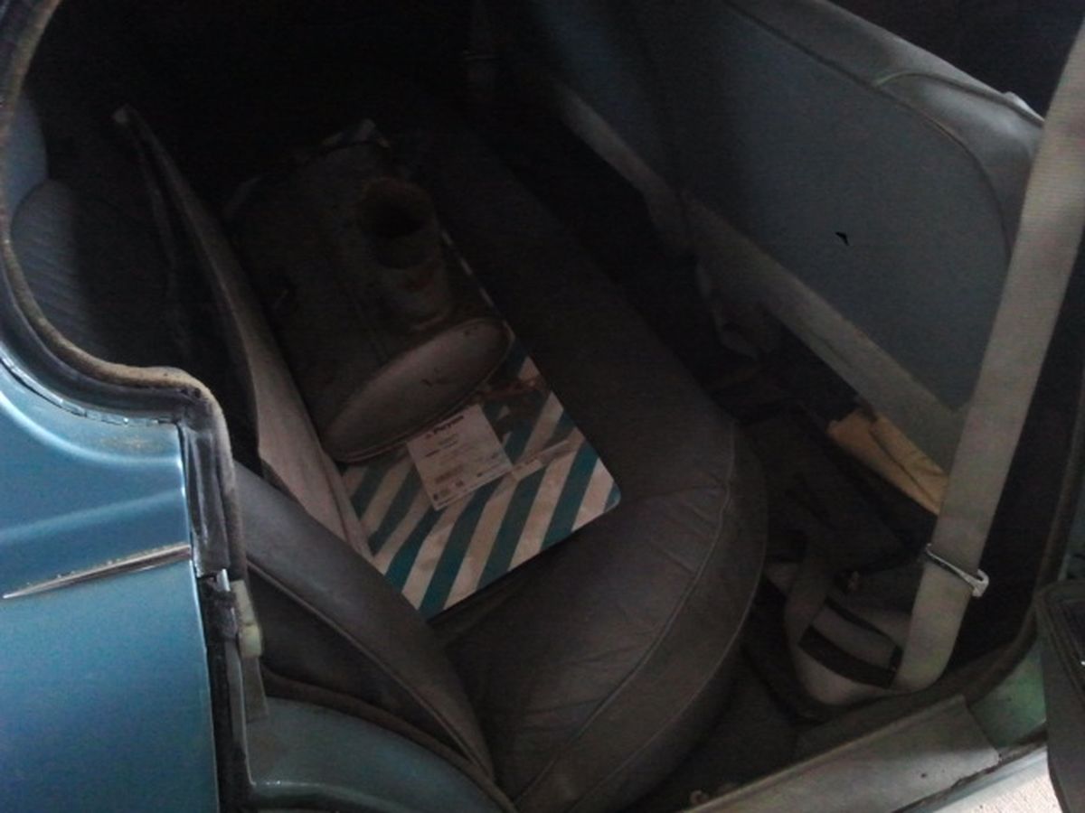 The back seat of a blue car with a box on the seat