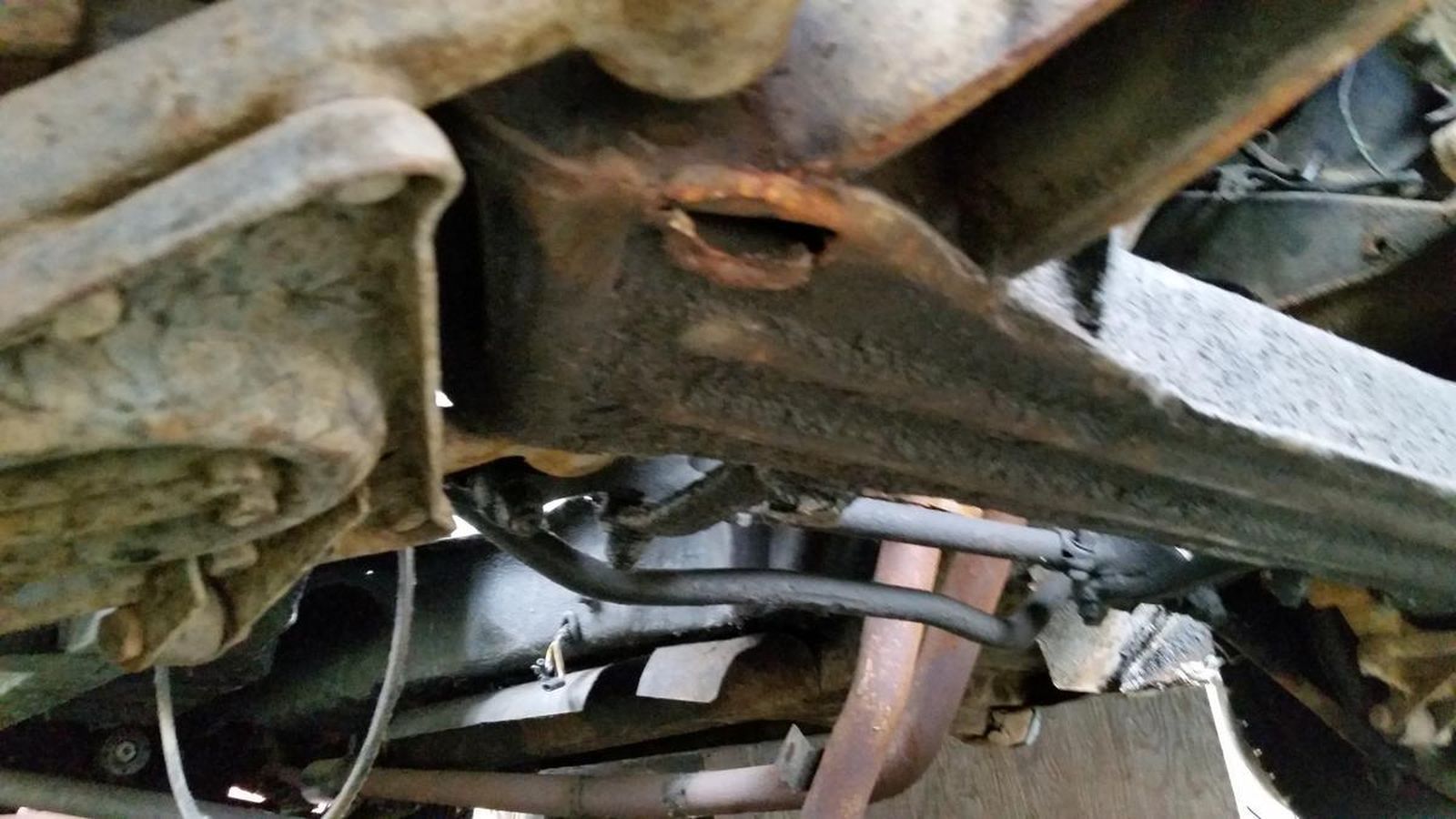 A close up of the underside of a car with a hose coming out of it.