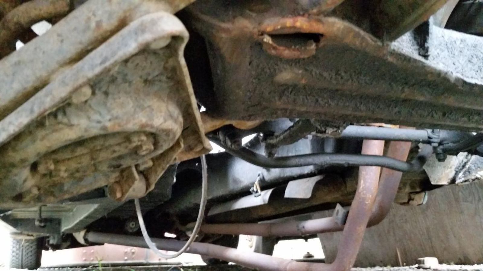 A close up of the underside of a car with a hose attached to it.