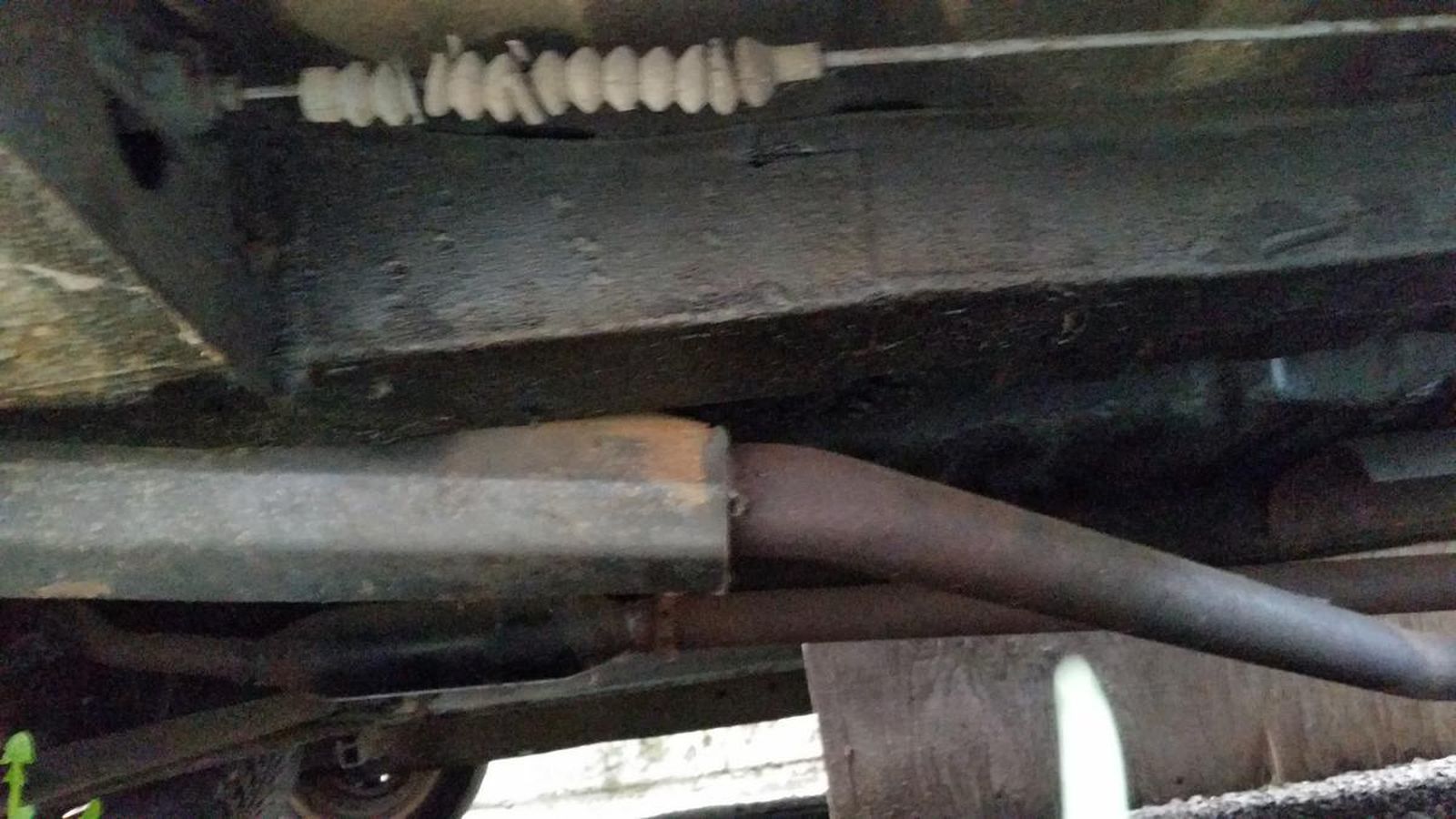 A close up of the underside of a car with a brake cable.