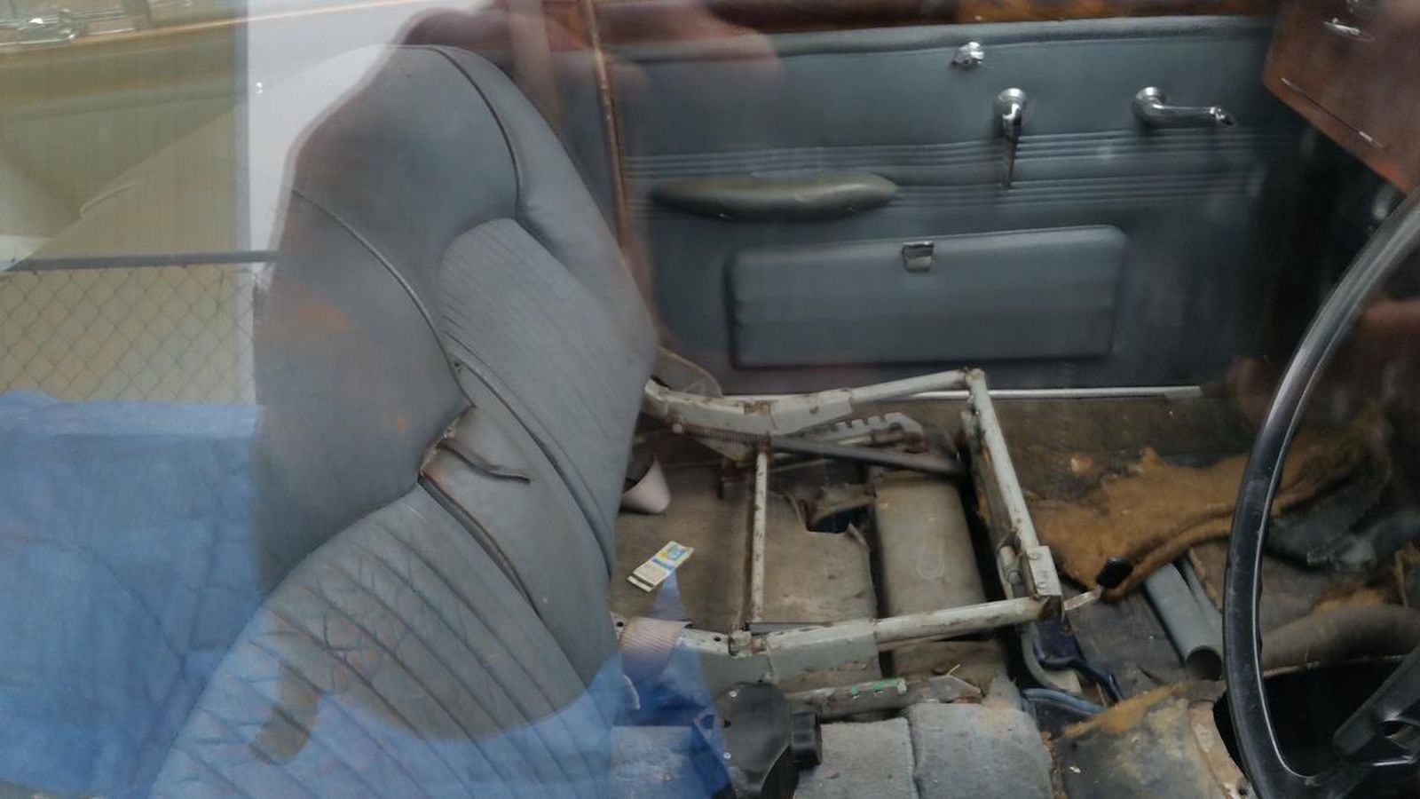 The inside of a car with a broken seat and a steering wheel.