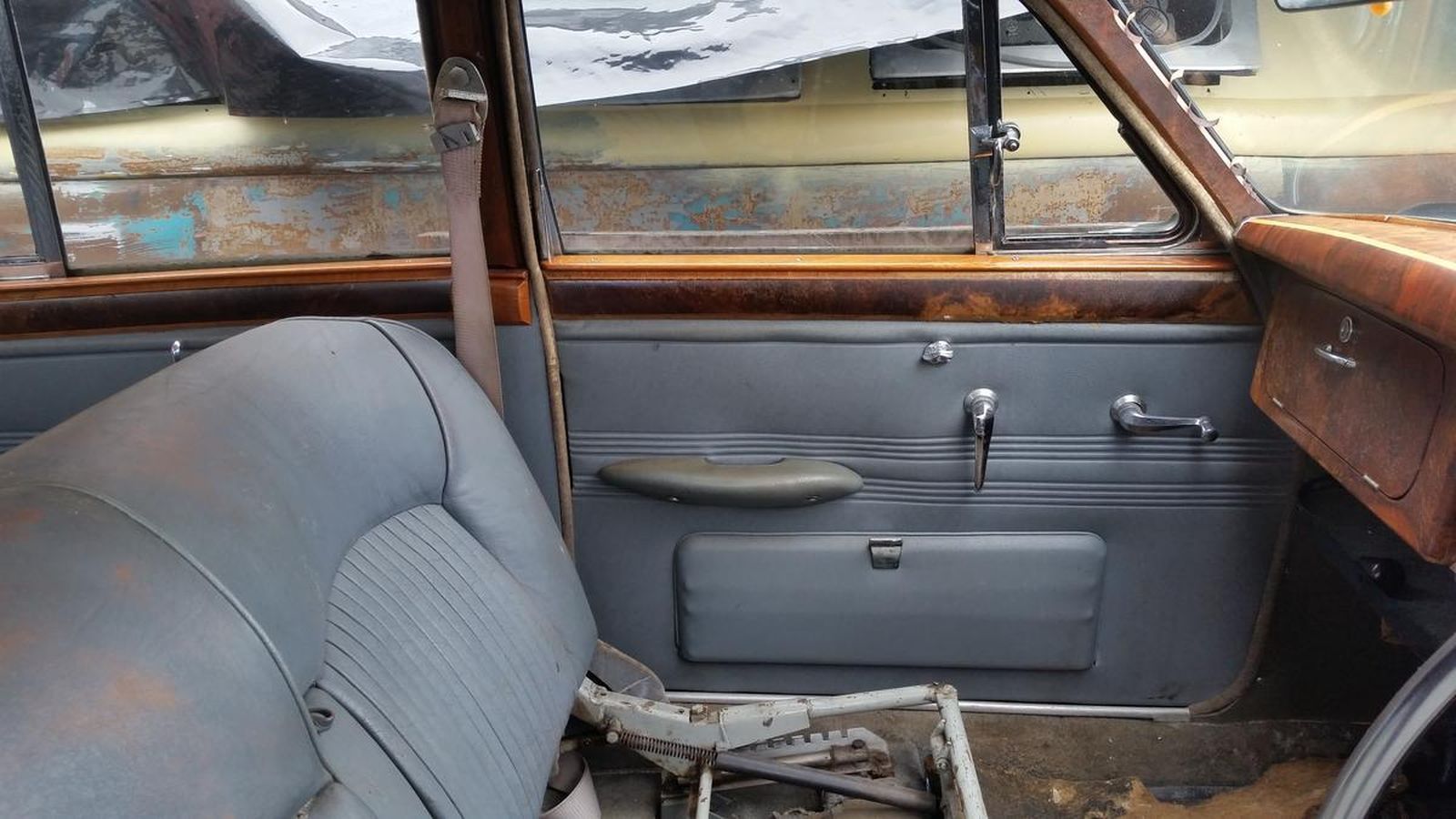 The inside of an old car with a broken seat.