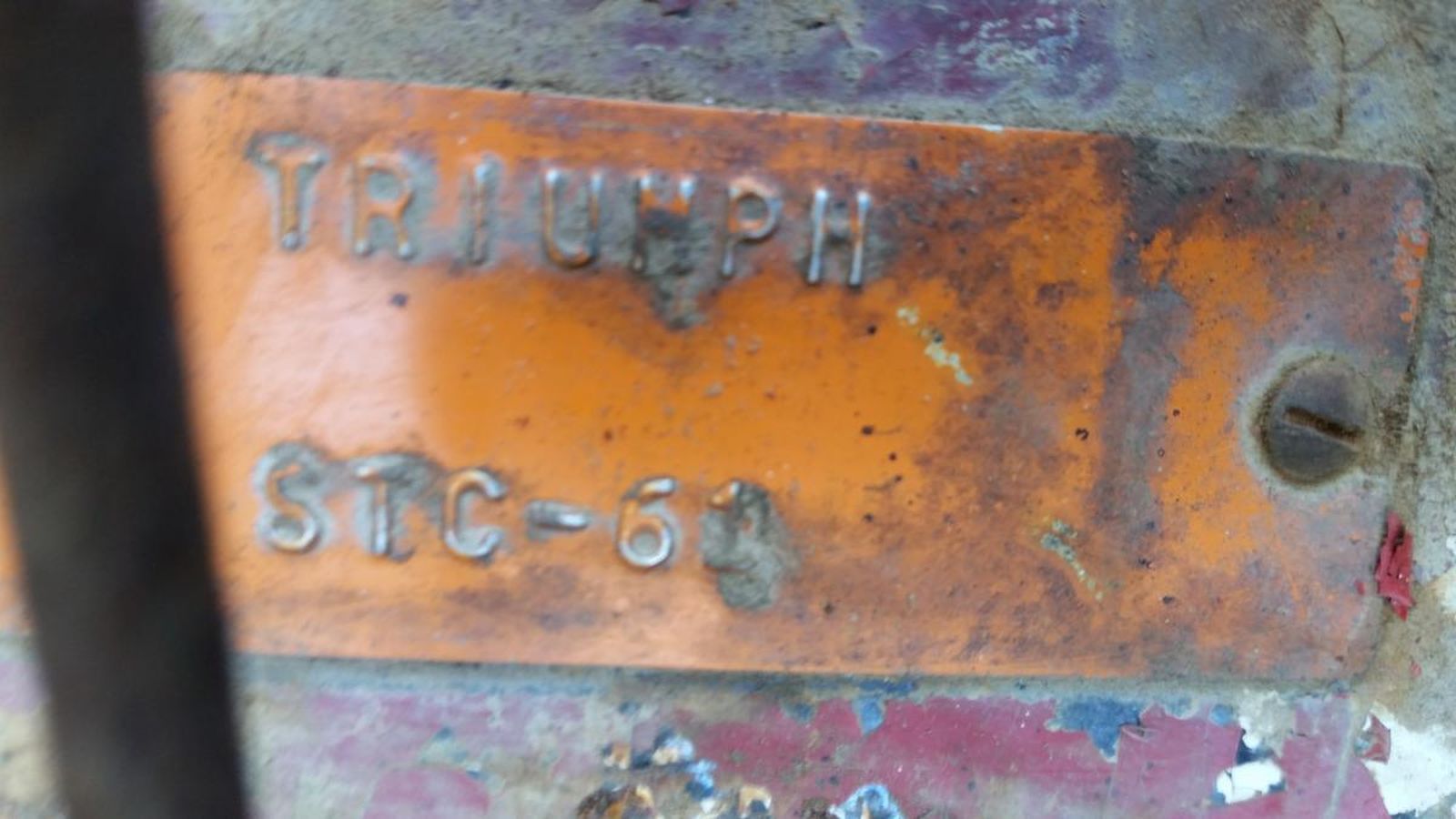 A close up of a rusty piece of metal with the word triumph written on it.