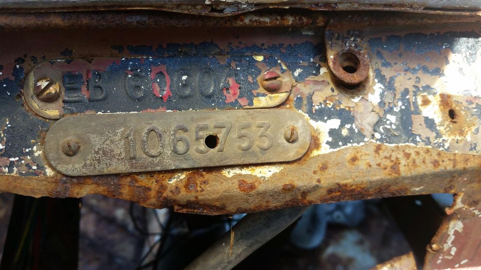 A rusty piece of metal with a license plate that says 106753 on it.