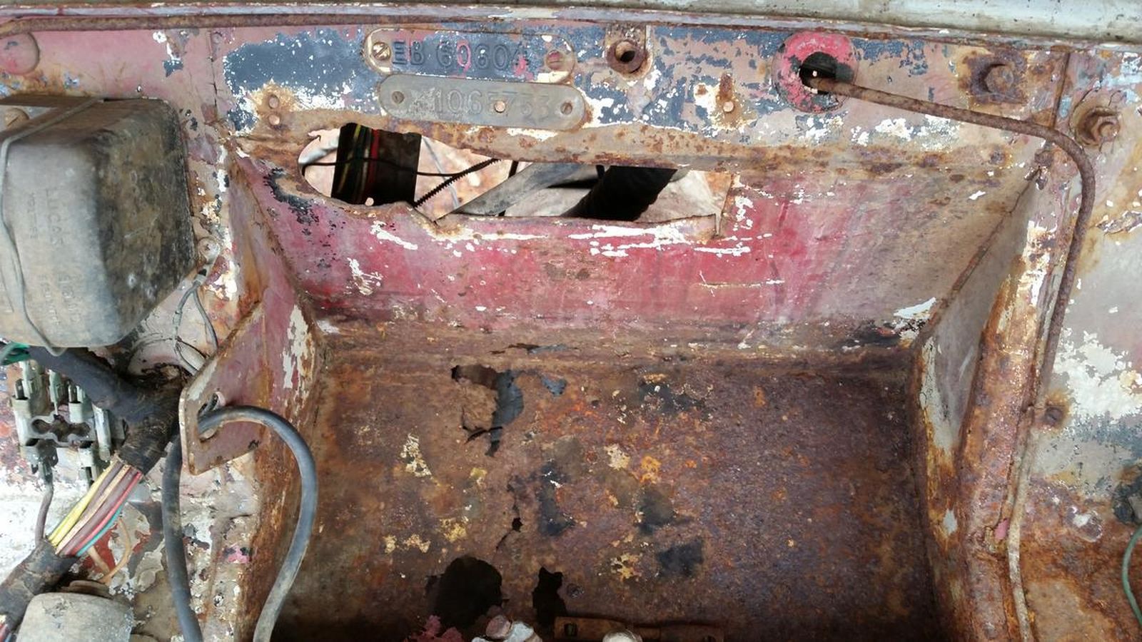 The inside of a rusty car with a few wires coming out of it.