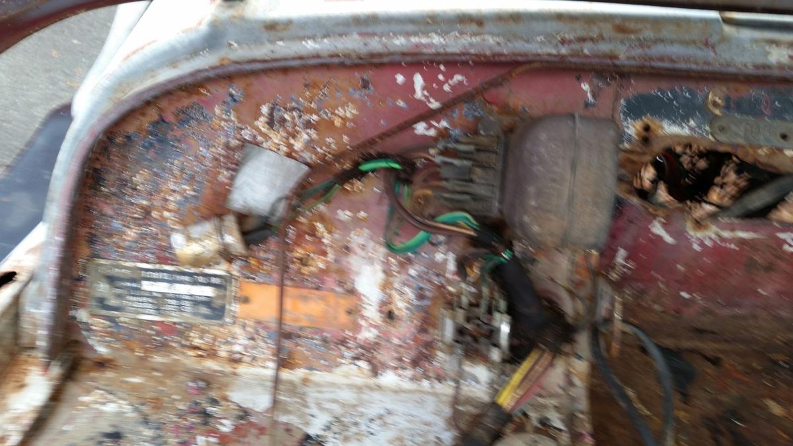 A close up of the inside of a rusty car.