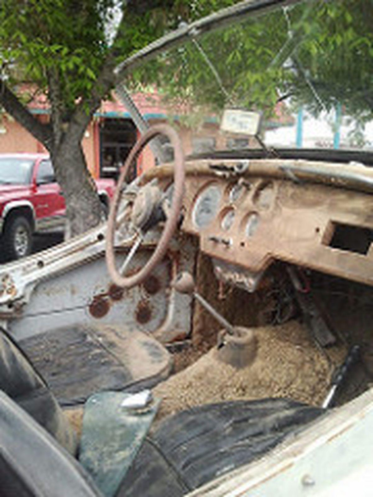 The inside of an old car with a steering wheel and dashboard.