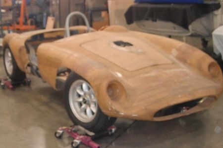 a wooden car is sitting on wheels in a garage