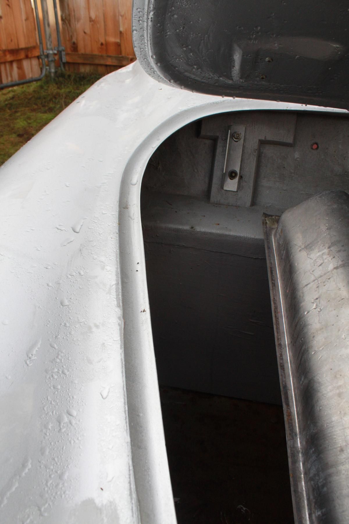 A close up of a white washing machine with a wooden fence in the background.