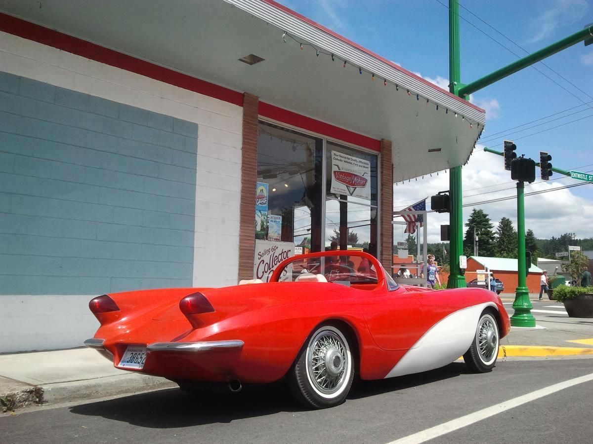 A red and white car is parked in front of a building