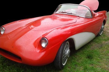 a red and white sports car is parked in the grass