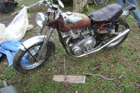 a motorcycle is parked in the grass with a person standing behind it .