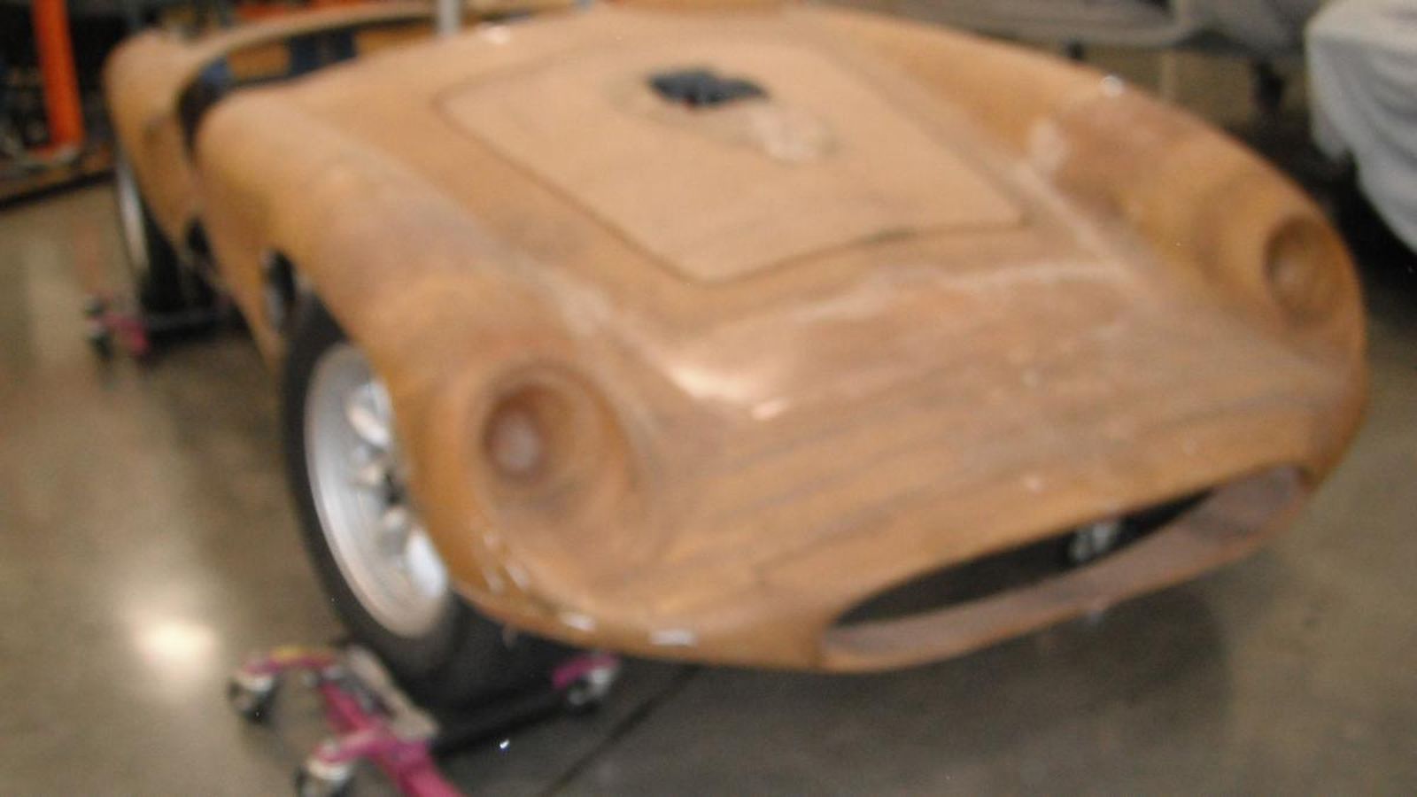 A wooden car is sitting on a concrete floor