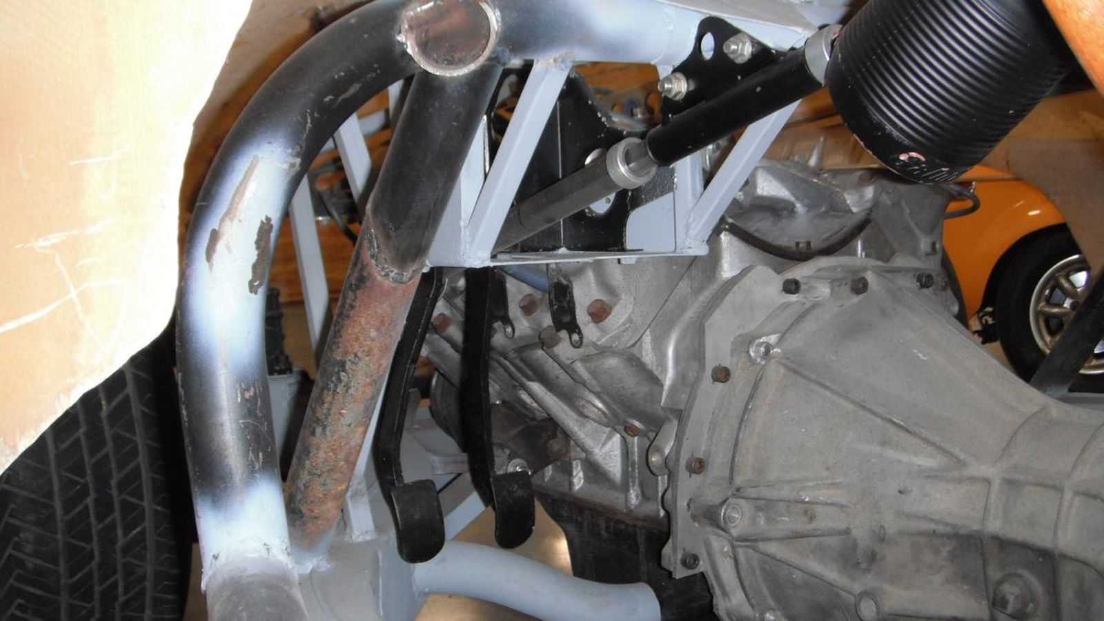 A close up of a car engine with a yellow car in the background