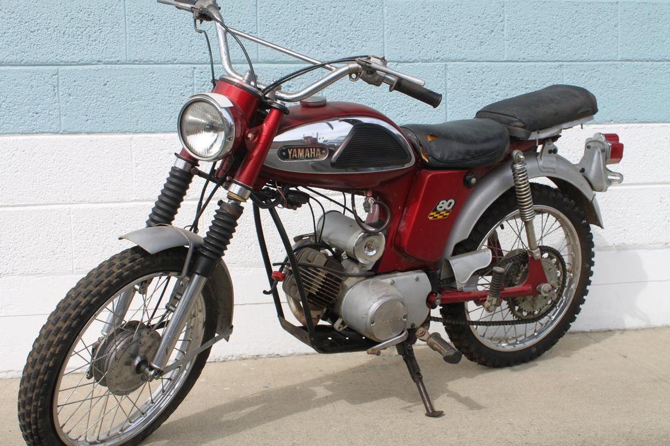 A suzuki motorcycle is parked in front of a brick wall