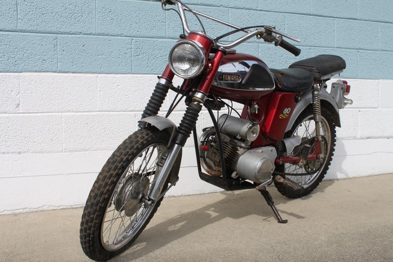 A red motorcycle is parked in front of a blue and white brick wall