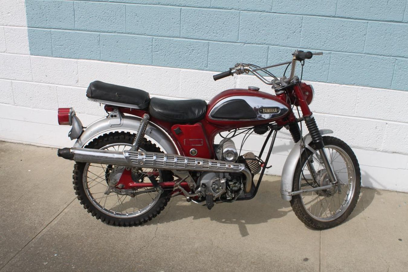 A red motorcycle is parked in front of a brick wall