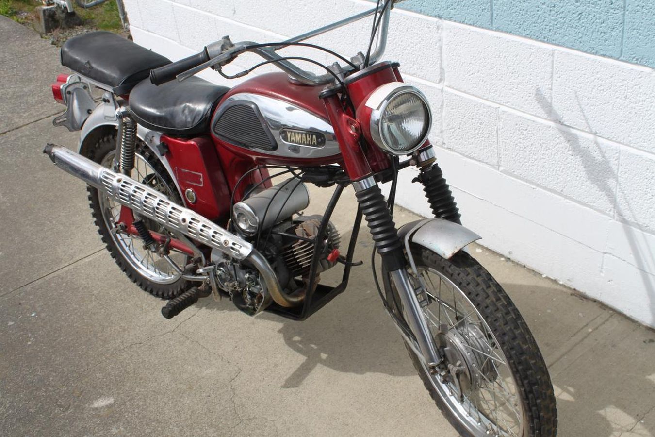 A red motorcycle is parked in front of a white brick wall