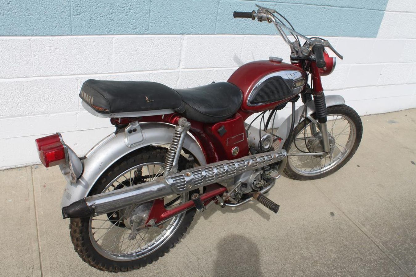 A red and silver motorcycle is parked on a sidewalk