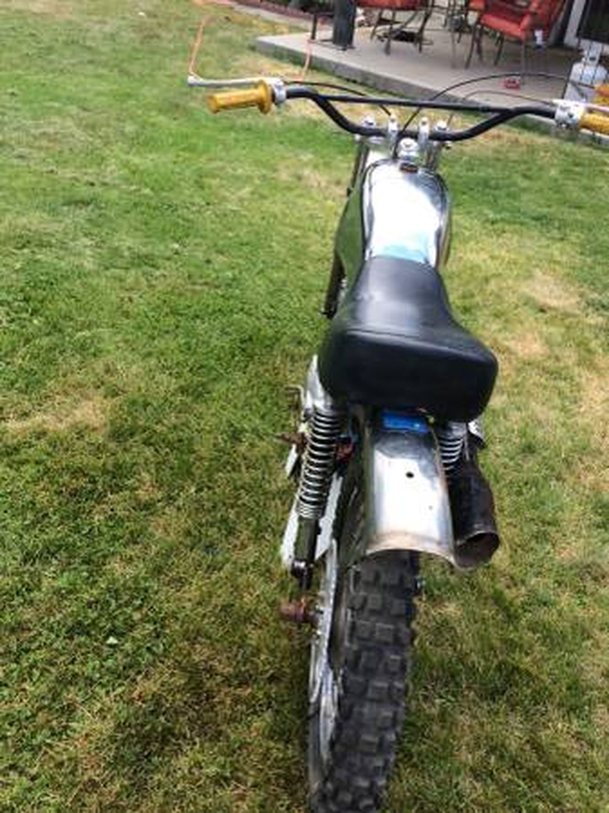 A dirt bike is parked in the grass in a yard.