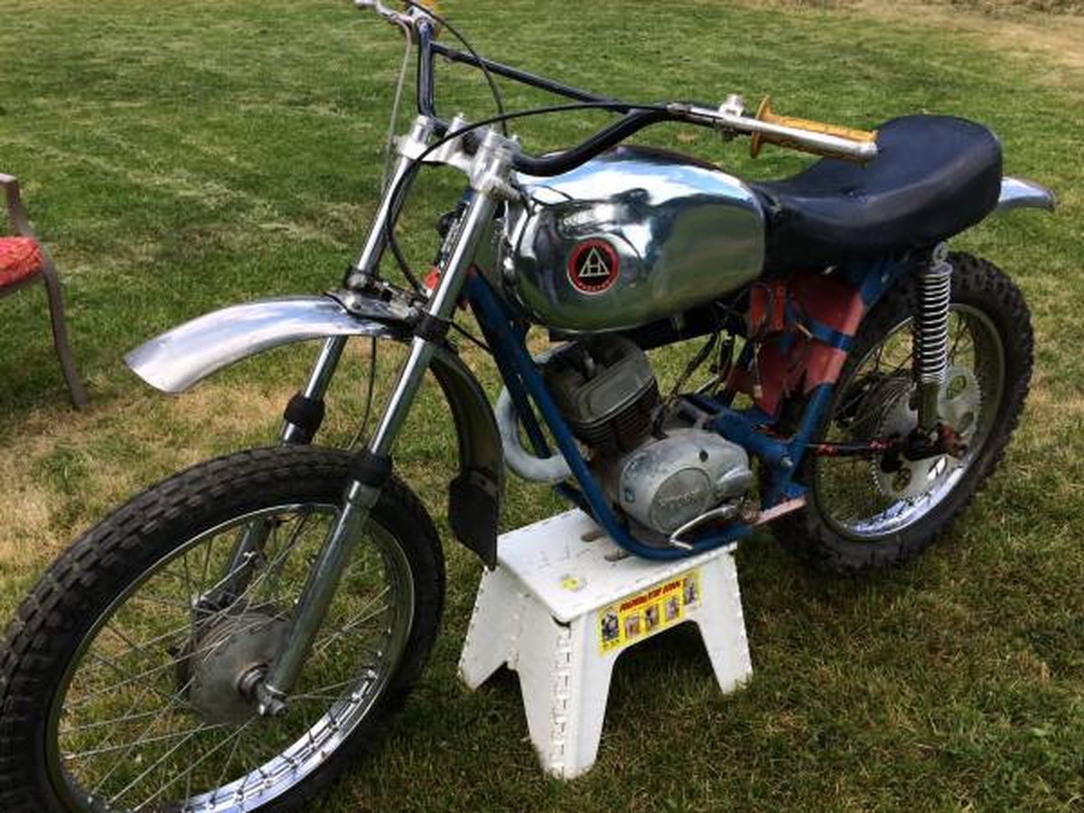 A dirt bike is parked on a white stool in the grass.