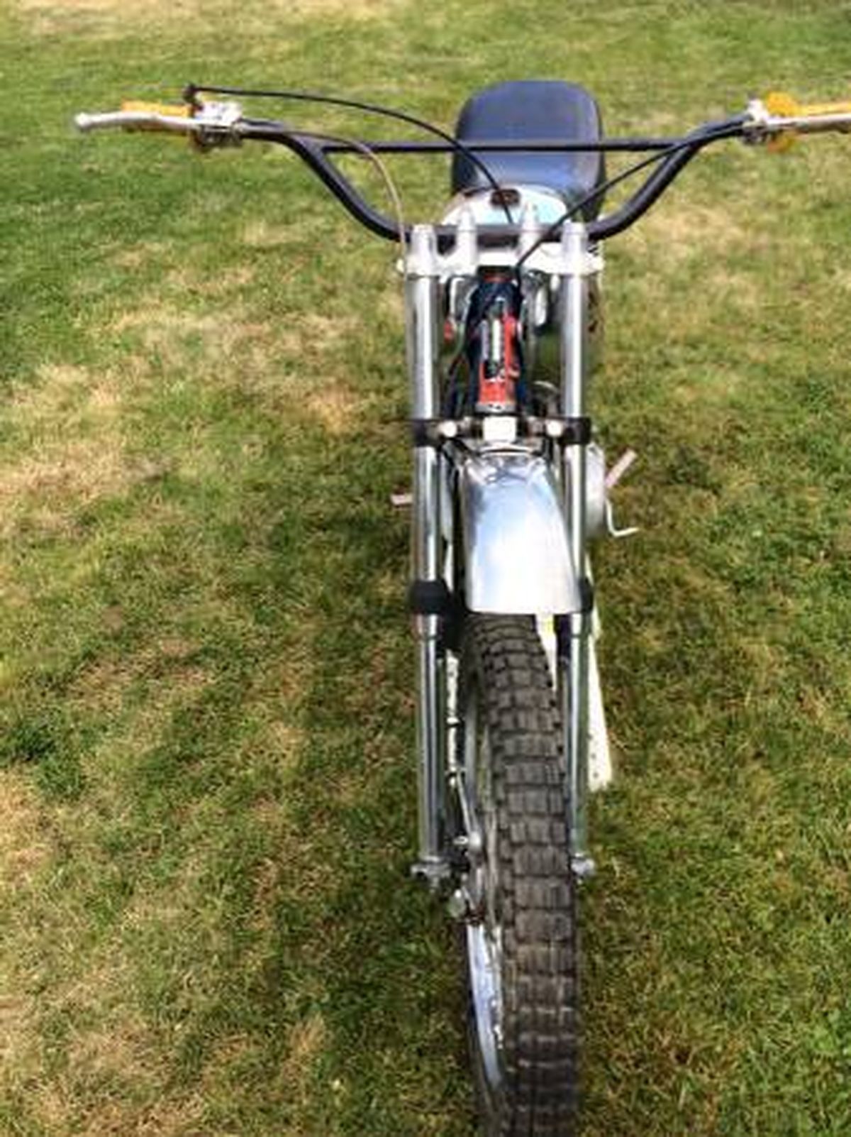 A motorcycle is parked in the grass in a field.