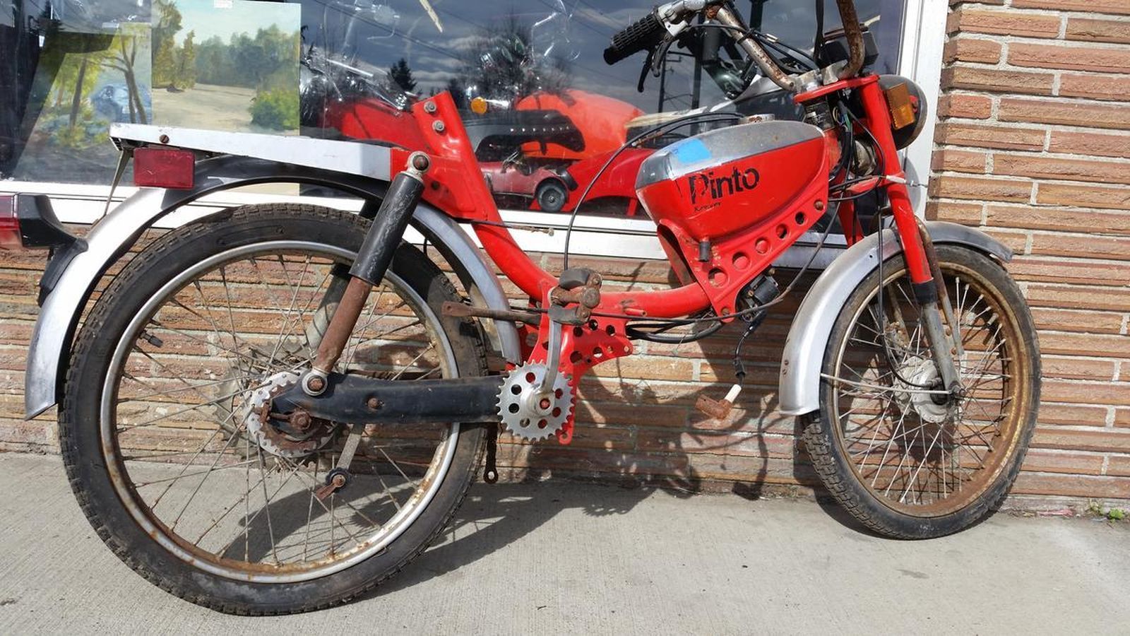 A red motorcycle is parked in front of a brick building