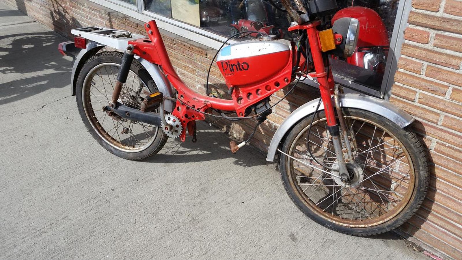 A red motorcycle is parked in front of a brick building