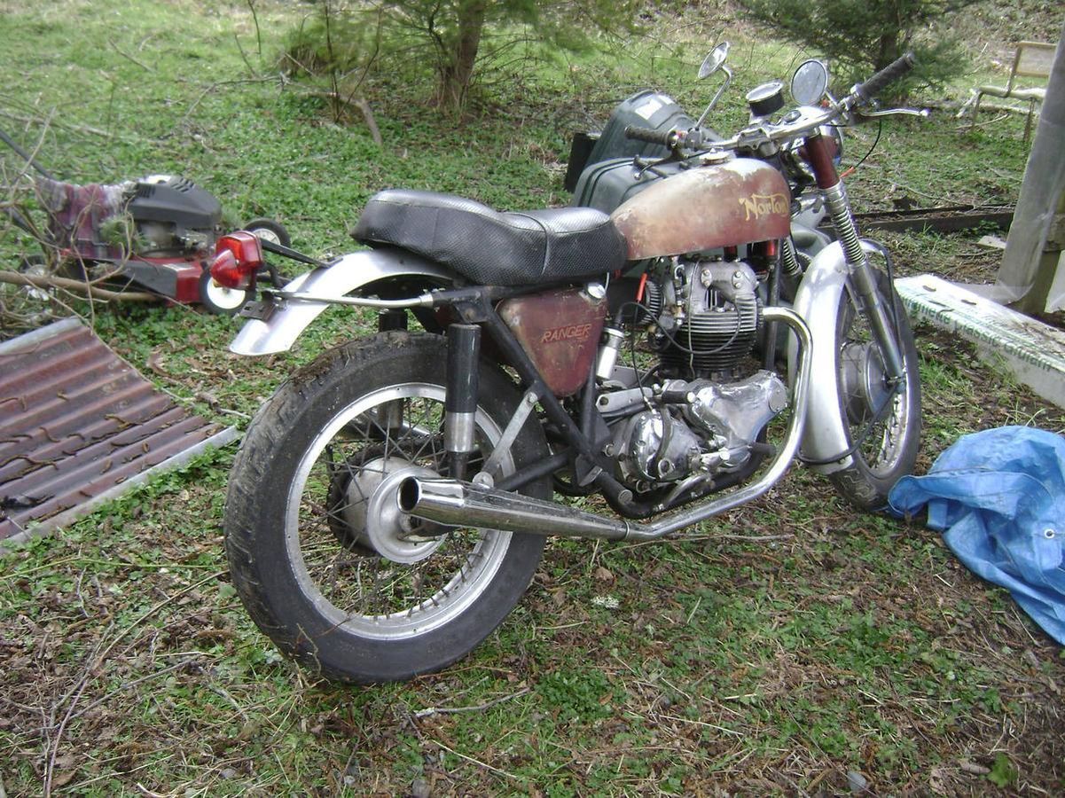 A motorcycle is parked in the grass next to a blue tarp.