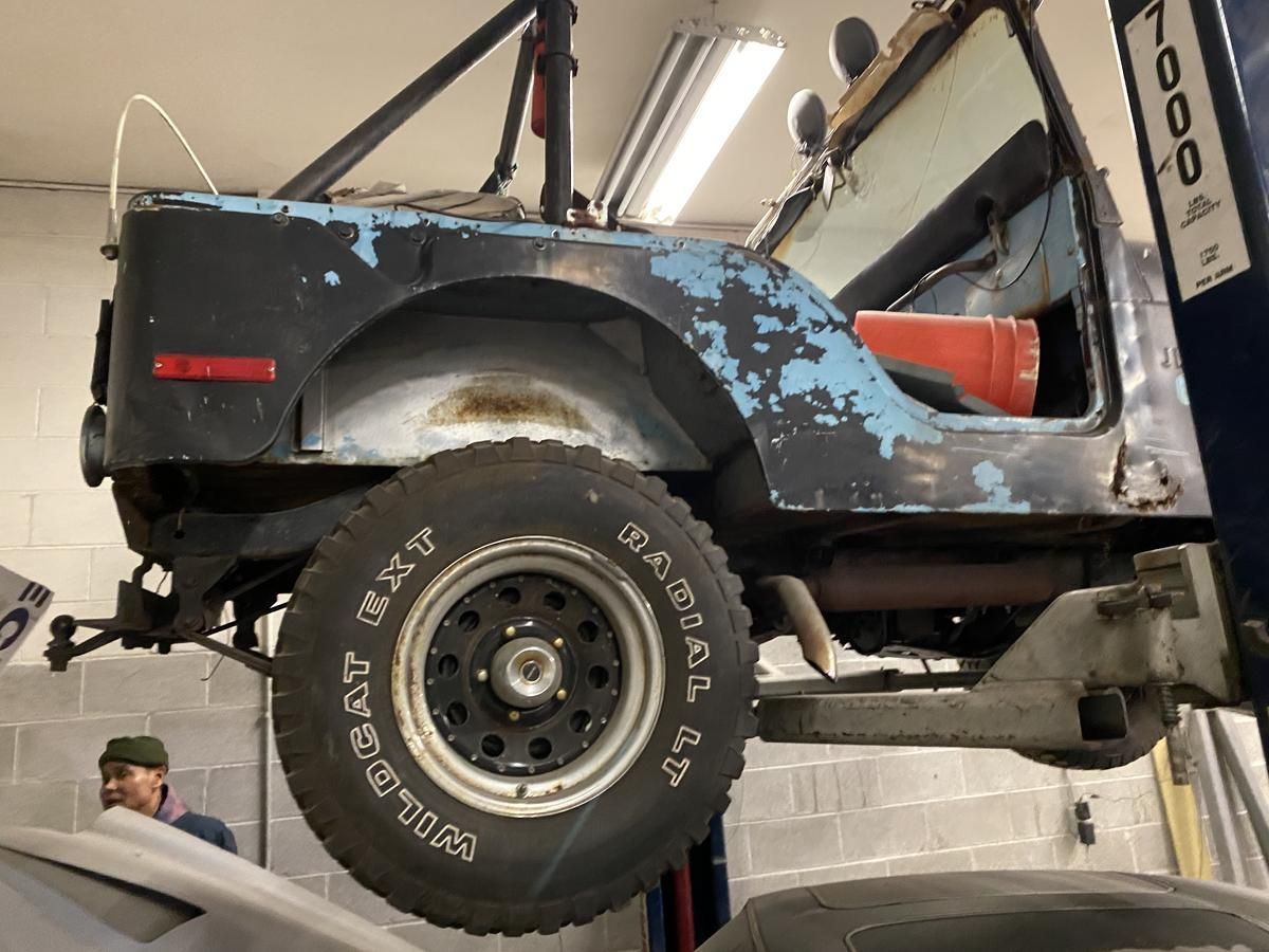 A jeep is sitting on a lift in a garage