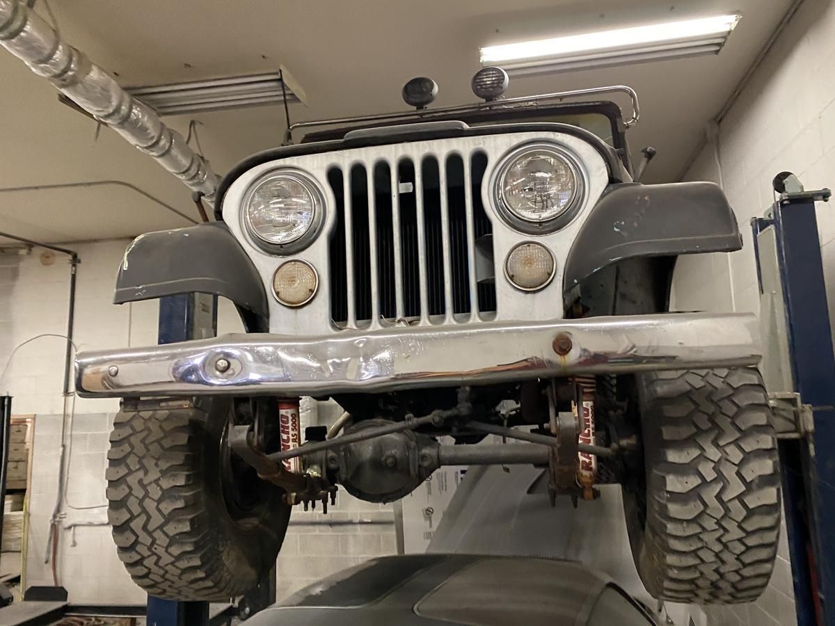 A jeep is sitting on a lift in a garage.