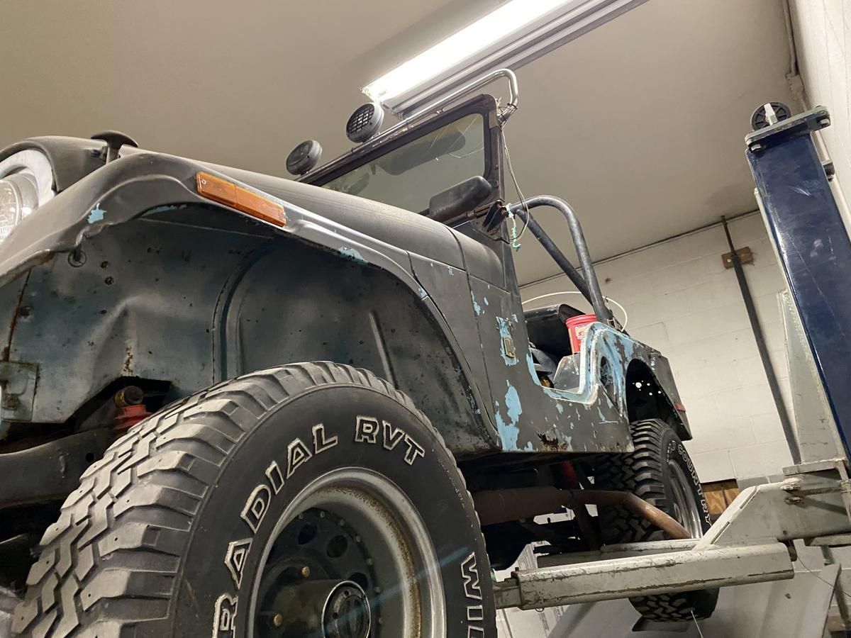 A jeep is sitting on a lift in a garage.