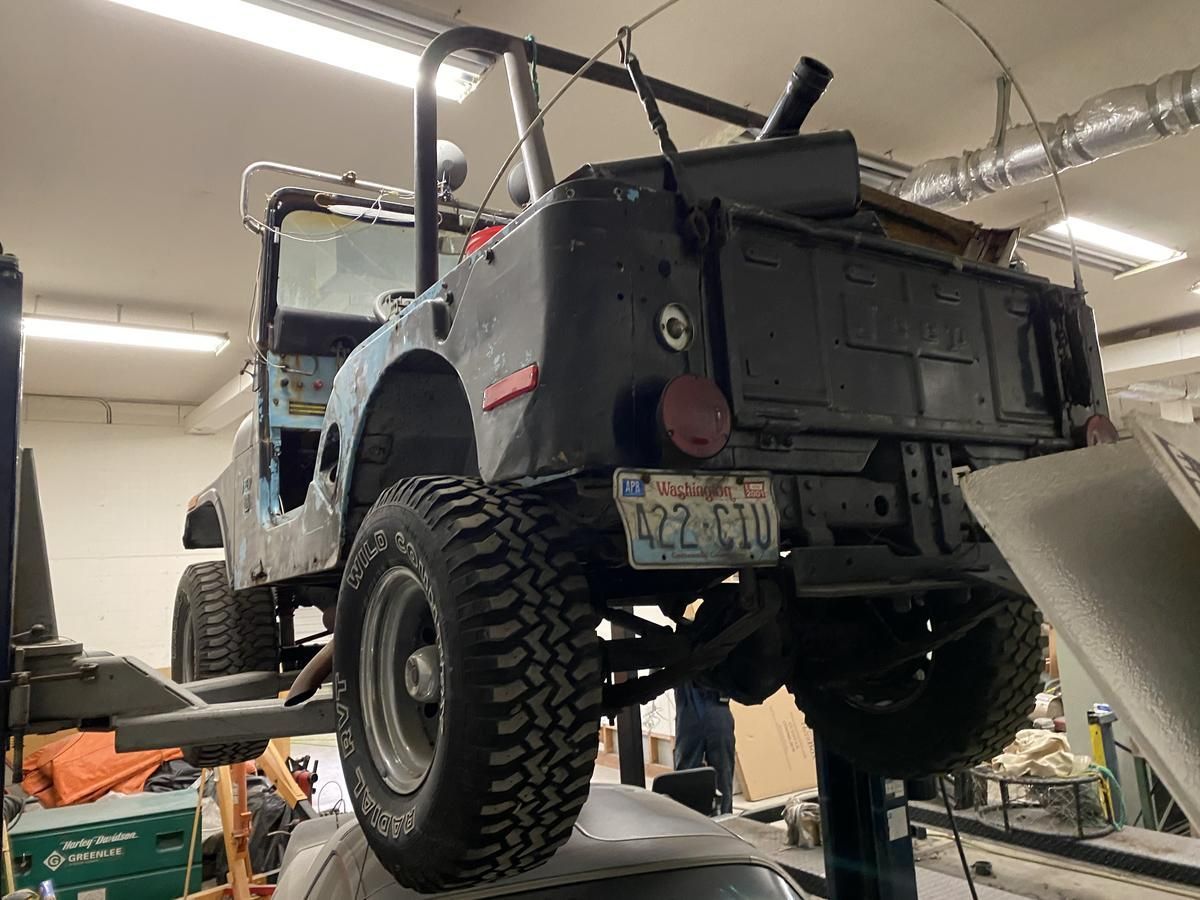 A jeep is sitting on a lift in a garage.