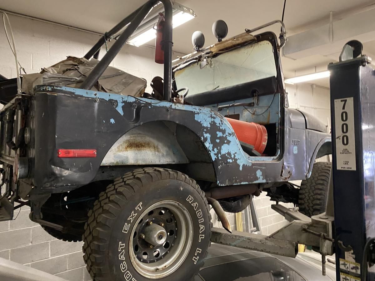 A jeep is sitting on a lift in a garage.