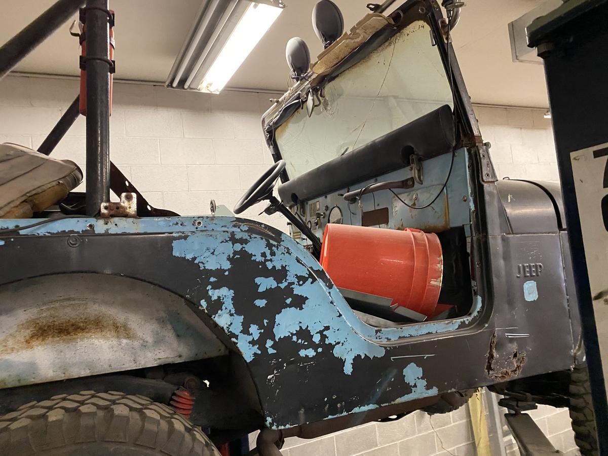 A jeep is sitting in a garage with the door open