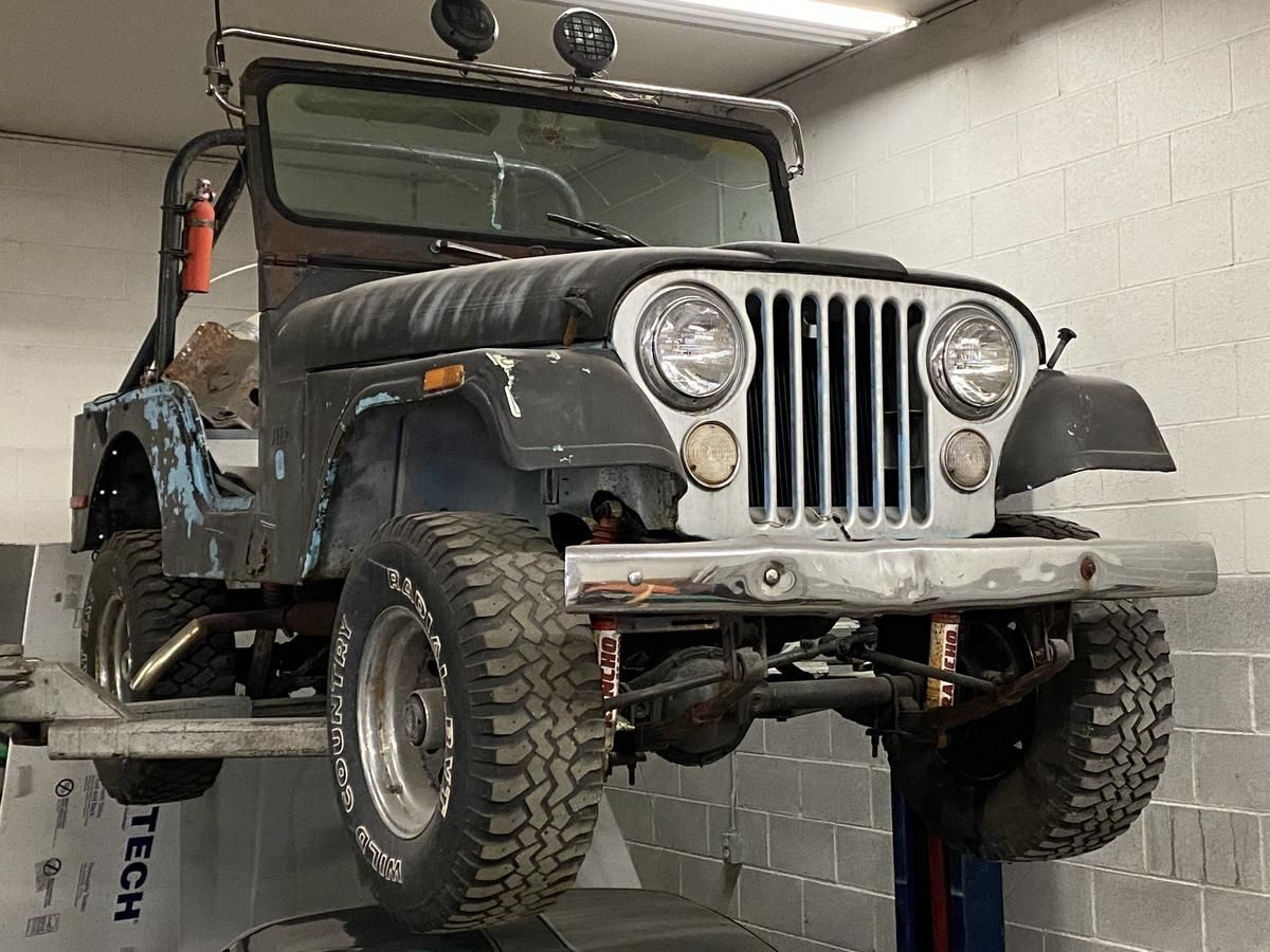 A jeep is sitting on a lift in a garage.