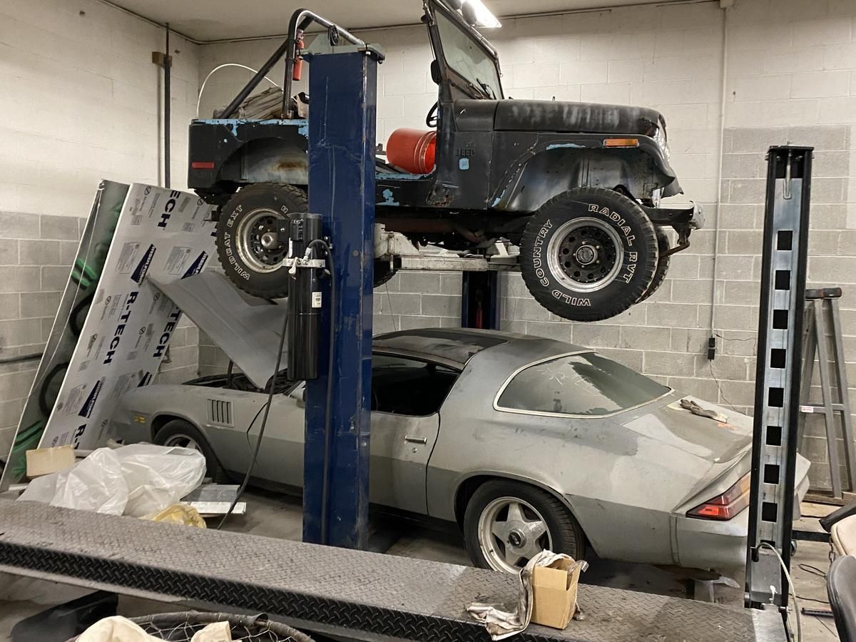 A jeep is sitting on top of a car on a lift.